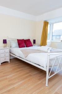 a white bed with red pillows in a bedroom at Spacious 2BR Home with Free Parking in Penwortham