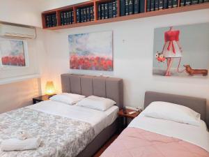 アテネにあるLovely apartment in Athens centerのベッドルーム1室(ベッド2台付)が備わります。壁には絵画が飾られています。