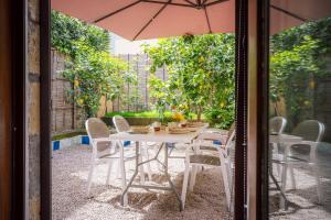 una mesa con sillas y una sombrilla en el patio en Maison Sersale, en Sorrento