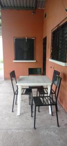 Country House in Los Planes. في Panchimalco: طاولة بيضاء وأربع كراسي أمام مبنى
