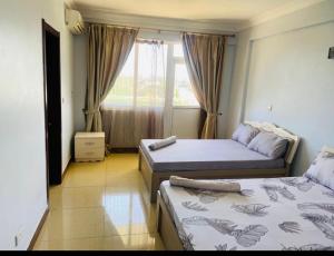 a bedroom with two beds and a window at Masaki Anne H & Apartment in Dar es Salaam