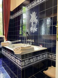 Baño de azulejos negros con bañera y lavamanos en Villa Puccini, en Venegono Superiore