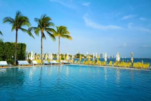 a large swimming pool with chairs and palm trees at The Standard Miami in Miami Beach