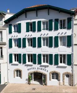 um edifício branco com persianas verdes em Hôtel Barnea em Biarritz