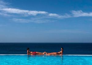 a man and woman laying in a swimming pool near the ocean at Appartamento Ferreira Stella Maris Exclusive in Calheta Do Maio +17 photos