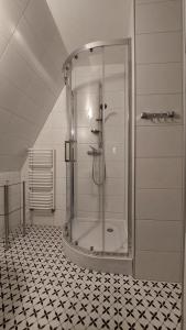 eine Dusche im Bad mit schwarzweißem Fliesenboden in der Unterkunft Willa Łuka in Wetlina