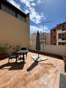 eine Terrasse mit einem Tisch und einem Sonnenschirm auf einem Gebäude in der Unterkunft B&B DaBi in Alghero