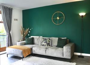 Modern Spacious Apartment في Thornton Heath: غرفة معيشة مع أريكة وساعة على جدار أخضر