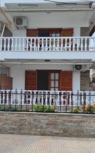 a white house with a balcony with flowers on it at Apartments Bella Casa in Paralia Katerinis