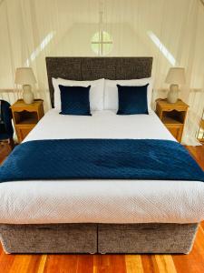 a bedroom with a large bed with blue sheets and pillows at De Búrca Cottage KERRY in Brackhill