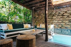 a patio with a couch and a table and stools at La Maison in Máncora