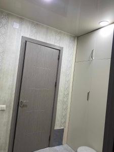 ein Bad mit einer Tür, einem WC und einem Schrank in der Unterkunft Apart Hotel ZUKA in Kobuleti
