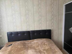 ein Bett mit schwarzem Kopfteil in einem Schlafzimmer in der Unterkunft Apart Hotel ZUKA in Kobuleti