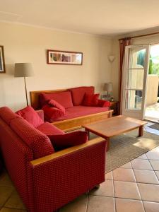 a living room with two red couches and a table at Les Maisons de Pont Royal en Provence - maeva Home - Maison climatisée pour 8 Personnes avec jardin privatif et terrasse MAE-2283 in Mallemort
