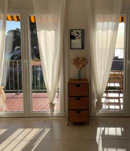 Habitación con 2 ventanas grandes con cortinas blancas. en Appartement cosy vue mer à 50 m de la plage - refait à neuf et climatisé, en Le Pradet