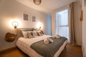 1 dormitorio con 1 cama con 2 toallas en Le Palmae, appartement cosy, cœur de ville, climatisé, en Hyères
