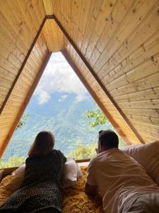 Ein Mann und eine Frau sitzen auf einem Bett und schauen aus dem Fenster in der Unterkunft cottage panorama merisi in Inasharidzeebi