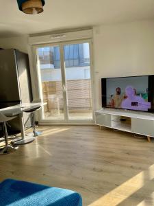 a living room with a large flat screen tv at Chambre Confort - Douche Privative - Jardin - Parking Gratuit in Argenteuil