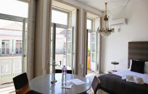 Schlafzimmer mit einem Bett, einem Tisch und Fenstern in der Unterkunft Palácio Fenizia Lux Apartments in Porto