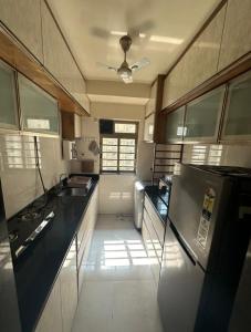 Il comprend une cuisine équipée d'un comptoir noir et d'un réfrigérateur. dans l'établissement 1-BHK:Where Comfort Meets luxury, à Mumbai