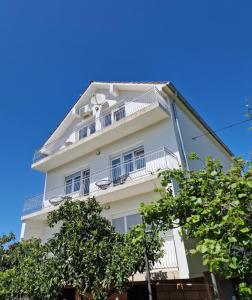 a white building with balconies and trees at Apartmani Zinda in Sukošan