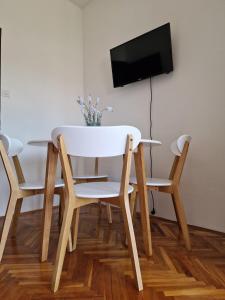 d'une table avec deux chaises et d'une télévision murale. dans l'établissement Apartmani Zinda, à Sukošan