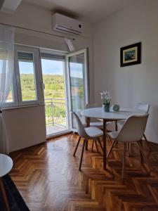 a dining room with a table and chairs and a balcony at Apartmani Zinda in Sukošan