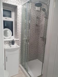 a bathroom with a glass shower and a sink at Glorioushome in Basildon