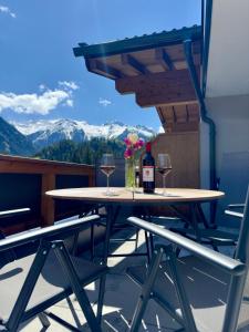 a table with two glasses of wine and flowers on a balcony at Apartment Waldherz in Wald im Pinzgau