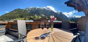 una mesa con 2 copas de vino y flores en el balcón en Apartment Waldherz, en Wald im Pinzgau