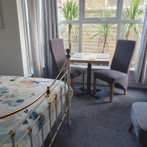 a bedroom with a table and chairs and a bed at Chynoweth Lodge in Newquay