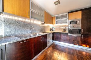 a kitchen with wooden cabinets and stainless steel appliances at Modern Luxury Townhouse 3 Bedroom Townhouse Olhos de Agua Communal pool AT03 in Olhos de Água