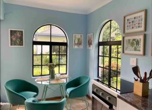 a room with a table and chairs and two windows at Cottage in a beautiful South African garden in Pretoria