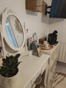 um toucador branco com um espelho e um vaso de plantas em Chambre d'hôtes kaxu em Bassussarry