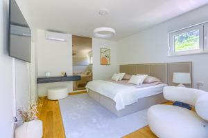 a white bedroom with a bed and two chairs at Villa A&D in Slatine