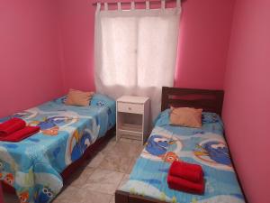 2 camas individuales en una habitación con paredes rosas en Departamento franco 3 en Los Antiguos