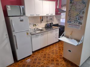a kitchen with white appliances and a wooden floor at Departamento franco 3 in Los Antiguos