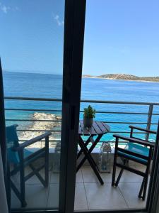 einen Tisch und Stühle auf einem Balkon mit Meerblick in der Unterkunft Perla Apartments in Agios Nikolaos
