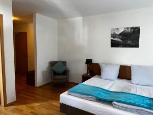 a bedroom with a bed and a chair at Hotel Sonne in Neuburg