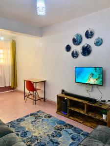 a living room with a flat screen tv and a table at Cozystay in Nakuru