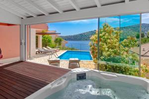 a house with a hot tub on a deck with a view at Beachfront Vila Angelina in Vinišće