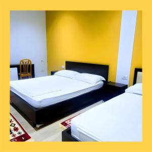 a bedroom with two beds and a yellow wall at VILA LILI Guest House - Berat in Berat
