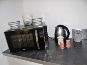 a microwave sitting on a counter with dishes on it at Gîte pour 2 personnes le domaine de la roquette près de fécamp à ganzeville in Ganzeville