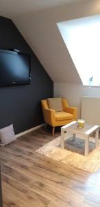 a living room with a tv and a chair and a table at Gîte pour 2 personnes le domaine de la roquette près de fécamp à ganzeville in Ganzeville