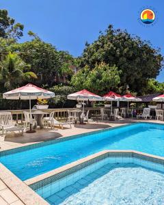 una piscina con tavoli, sedie e ombrelloni di Pousada Ponta de Areia a Vila Velha