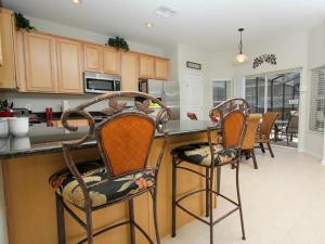uma cozinha com um balcão com cadeiras e um balcão em Archfeld Villa 2505 em Orlando
