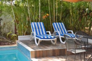 3 Stühle und ein Tisch neben einem Pool in der Unterkunft Casa Kiin in Chichimilá