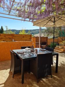 a table with chairs and an umbrella on a patio at Maison classée 2 étoiles proche du lac du Salagou in Clermont-lʼHérault