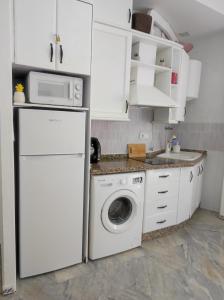 a kitchen with a washing machine and a microwave at Apartamentos home Chipiona in Chipiona