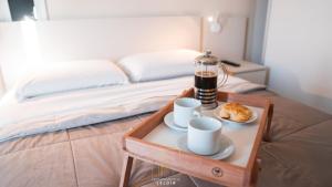 een dienblad met twee kopjes en een koffiezetapparaat op een bed bij Departamentos Leloir in Neuquén